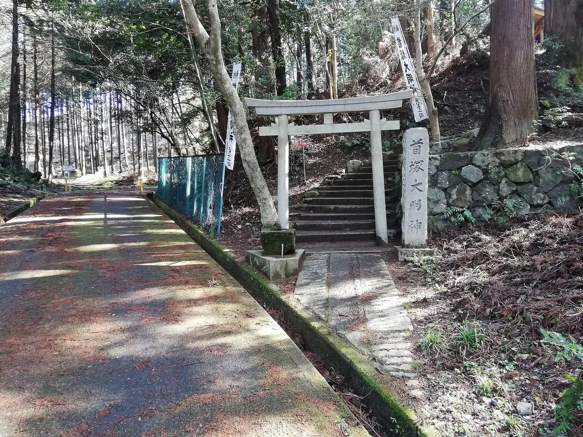 老ノ坂峠の首塚大明神の入口。石段の手前に白い鳥居と「首塚大明神」と刻まれた石柱が立っている