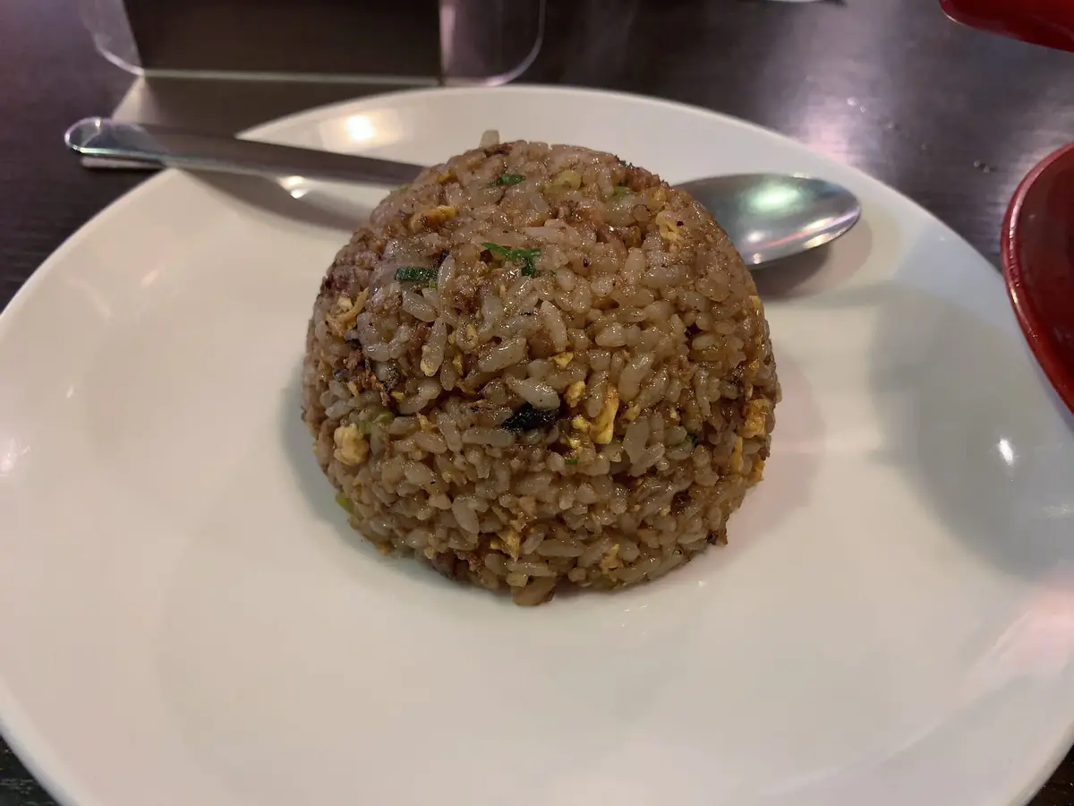 新福菜館のやきめし。醤油で濃い茶色に染まった炒飯が白い皿に丸く盛られている