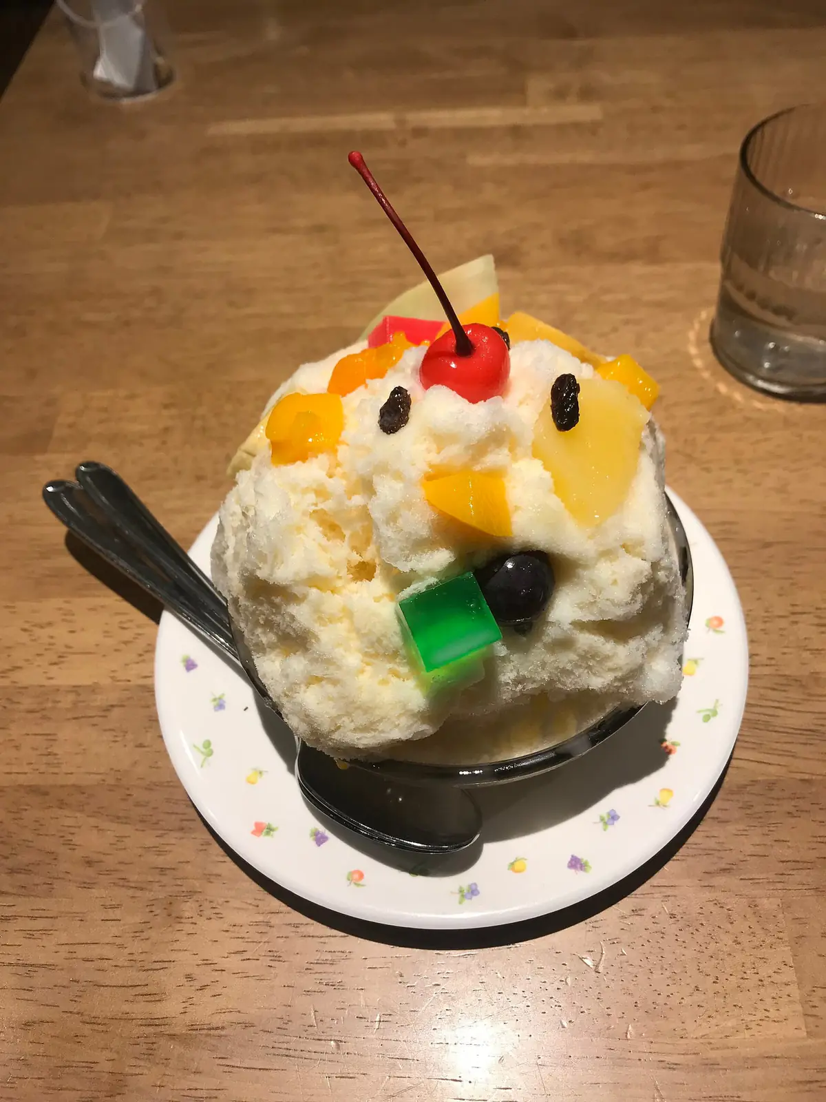 天文館むじゃきの白くま。練乳の氷の山にレーズンやチェリー、色とりどりのフルーツが盛られ、上から見ると目と鼻のように並んでいる