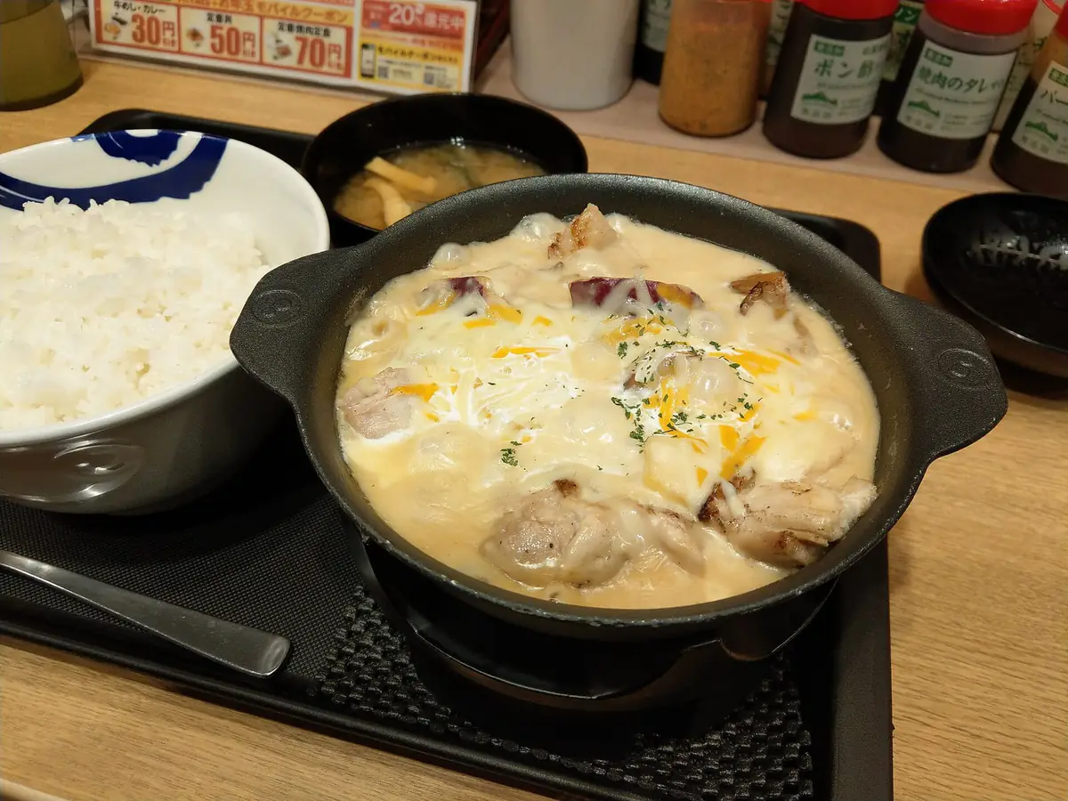 松屋で提供されたシュクメルリ。黒い鉄鍋に白いガーリックソースで煮込んだ鶏肉とサツマイモが入り、ライスと味噌汁が並んでいる